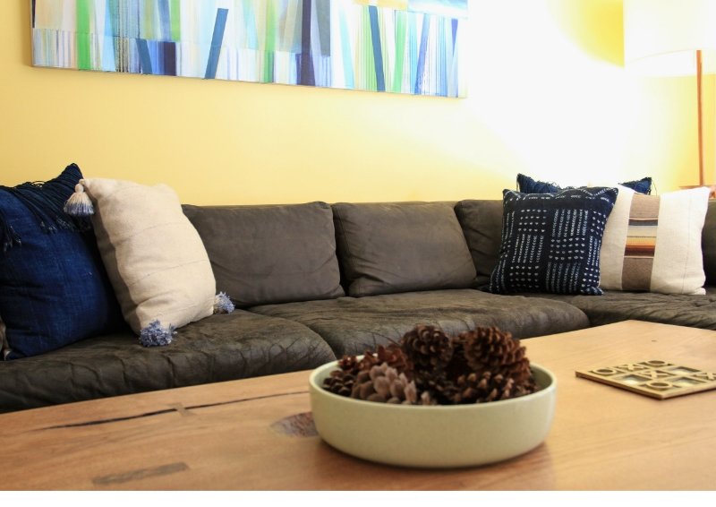 Vintage indigos paired with sunshine yellow make this den glow. Painting by LA artist Ned Evans. Wall color is Benjamin Moore Dalila. Client's own coffee table, sectional sofa, and floor lamp.&nbsp;